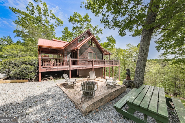 back of property with a wooden deck, a fire pit, and a patio area