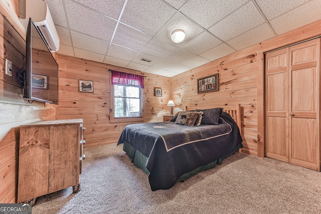 carpeted bedroom featuring a drop ceiling and wooden walls