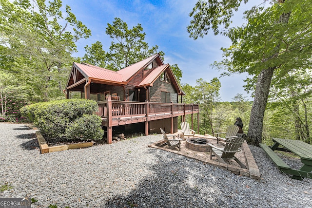 back of property featuring a fire pit and a deck