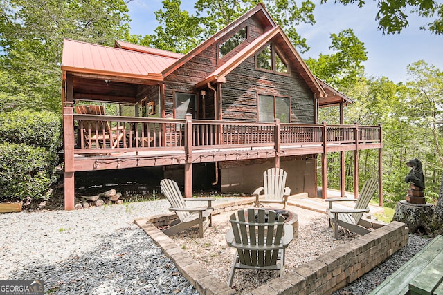 rear view of house with a patio, a wooden deck, and an outdoor fire pit