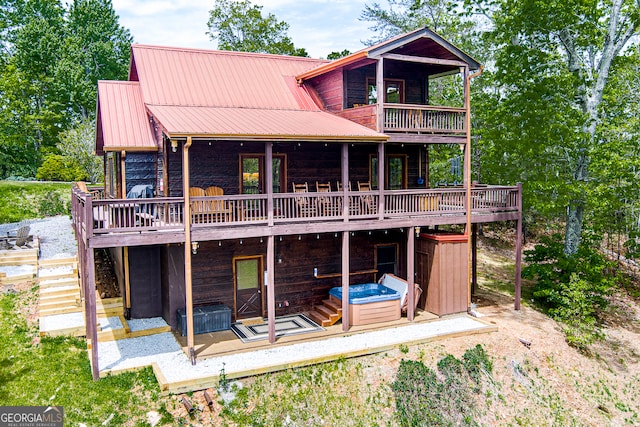 rear view of property with a deck and a hot tub