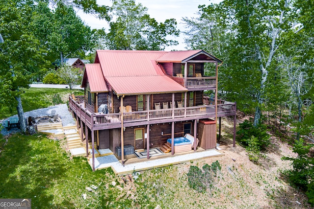 rear view of property with a hot tub and a deck