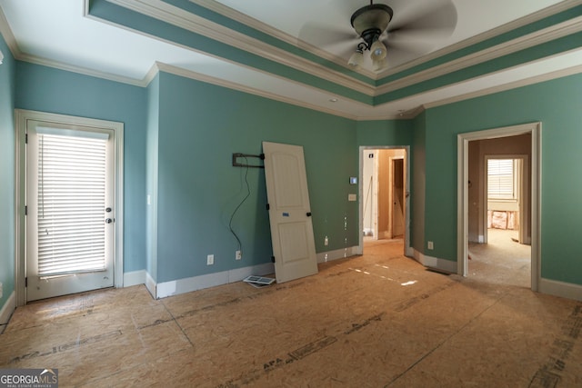 unfurnished bedroom with ceiling fan, multiple windows, a raised ceiling, and crown molding