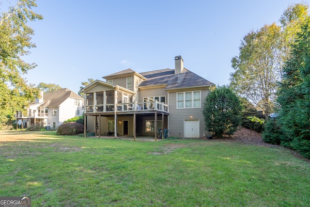 back of house featuring a sunroom, a lawn, and a wooden deck