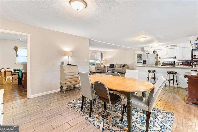 dining space with a textured ceiling and light hardwood / wood-style flooring