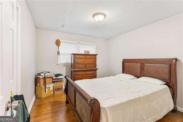 bedroom featuring dark hardwood / wood-style flooring and a textured ceiling