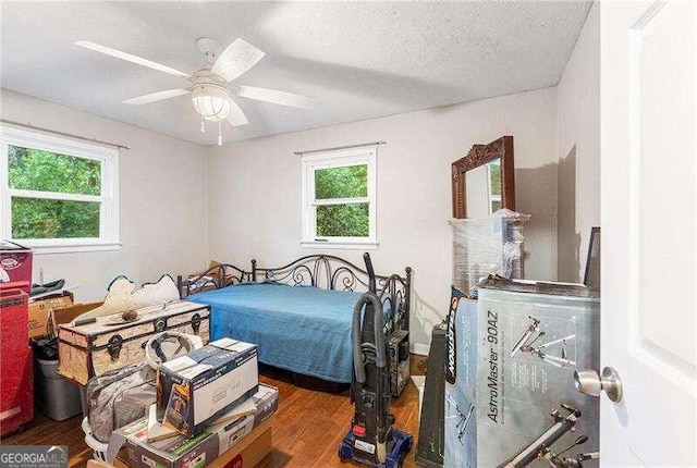 bedroom with multiple windows, a textured ceiling, ceiling fan, and dark hardwood / wood-style floors