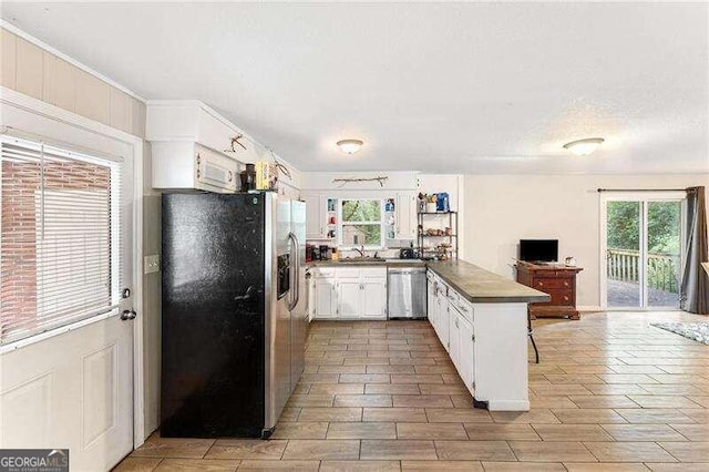 kitchen with stainless steel appliances, white cabinetry, and plenty of natural light