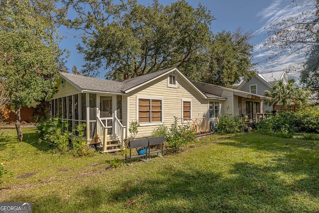 rear view of house featuring a lawn and a sunroom