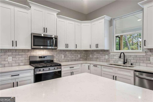 kitchen with tasteful backsplash, sink, white cabinets, and stainless steel appliances