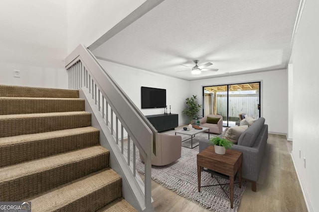 living room featuring hardwood / wood-style flooring, ceiling fan, and a textured ceiling