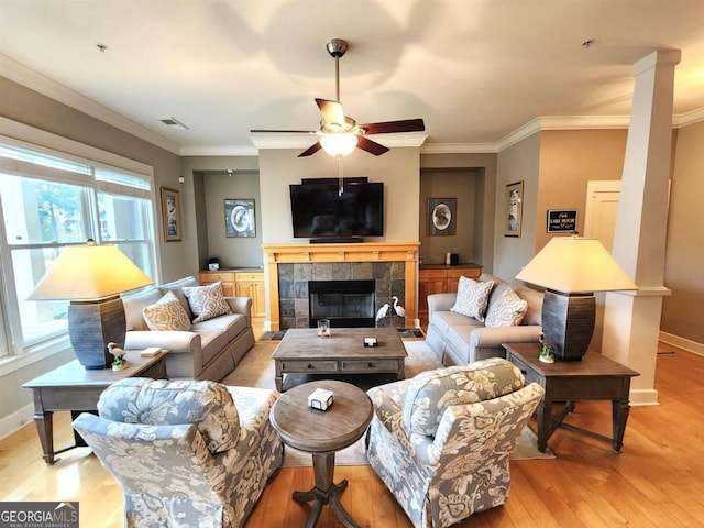 living room featuring ornamental molding, ceiling fan, light hardwood / wood-style floors, and a fireplace