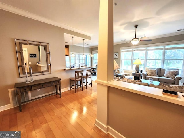 living room with crown molding, ceiling fan, and light hardwood / wood-style flooring