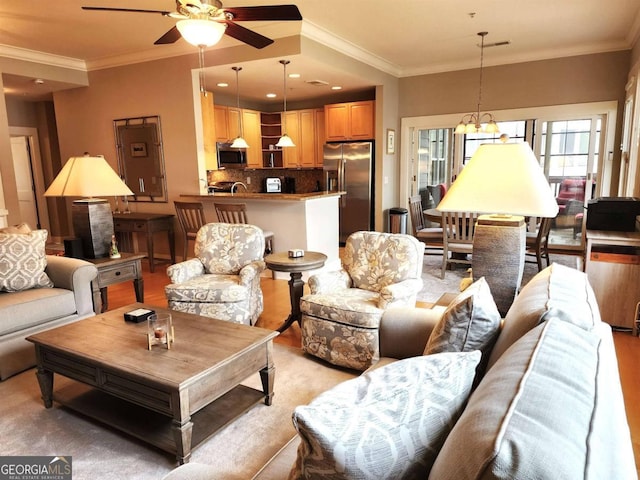 living room with ceiling fan with notable chandelier and crown molding