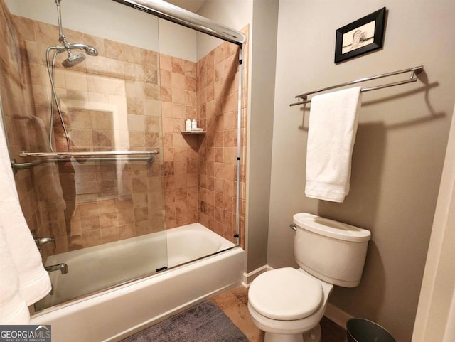 bathroom with shower / bath combination with glass door, tile patterned floors, and toilet