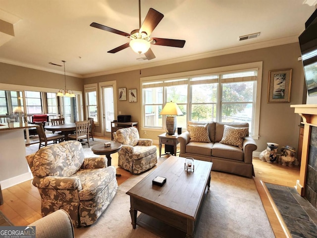 living room with ornamental molding, wood-type flooring, a healthy amount of sunlight, and ceiling fan