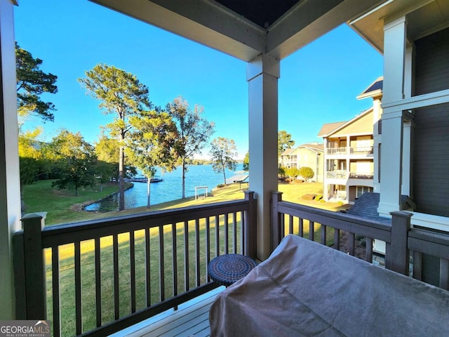 deck with a water view and a lawn