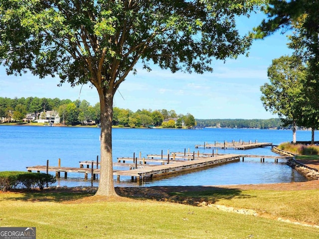 view of dock with a water view and a yard