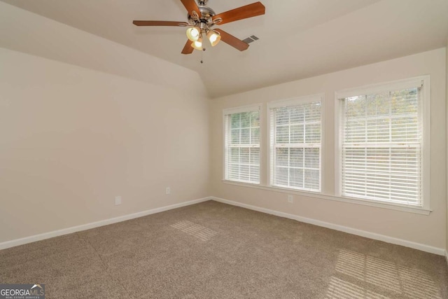 carpeted empty room featuring ceiling fan, vaulted ceiling, and a healthy amount of sunlight