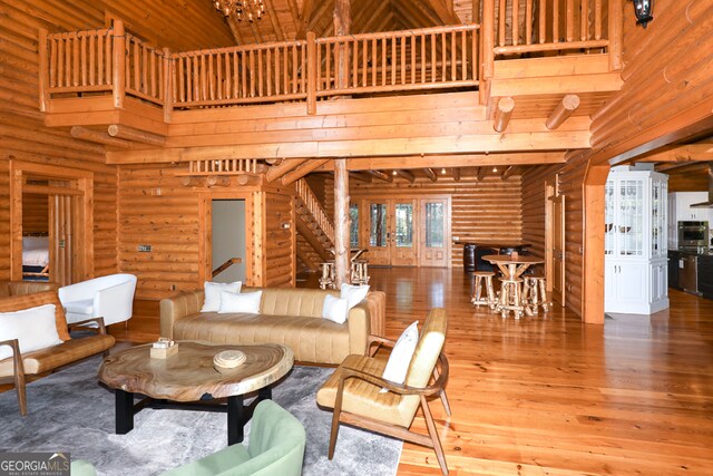 living room with rustic walls, hardwood / wood-style flooring, and a towering ceiling