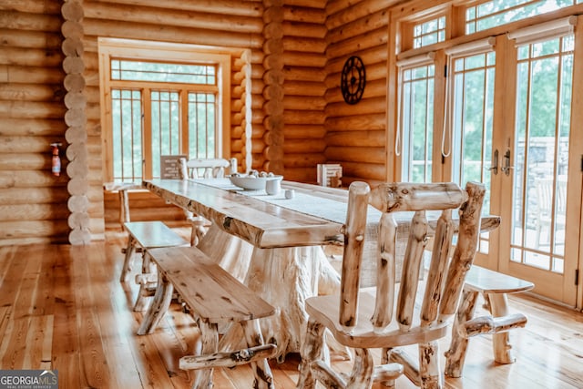 dining room featuring light hardwood / wood-style floors, a healthy amount of sunlight, and log walls