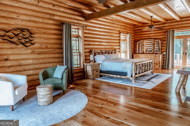 bedroom with hardwood / wood-style flooring, log walls, and beam ceiling