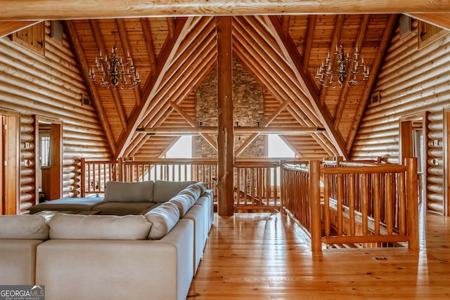 unfurnished living room featuring rustic walls, a notable chandelier, a healthy amount of sunlight, and light hardwood / wood-style flooring