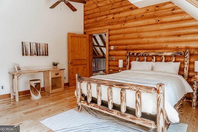 bedroom with ceiling fan, rustic walls, and light wood-type flooring