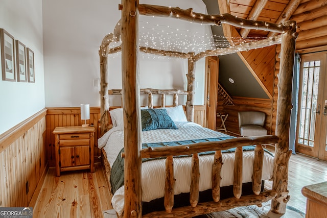 bedroom with wood walls, light hardwood / wood-style floors, wood ceiling, and vaulted ceiling