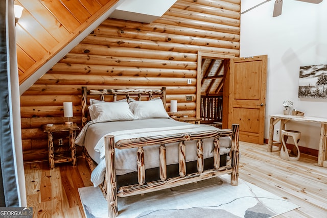 bedroom with rustic walls, hardwood / wood-style floors, and ceiling fan