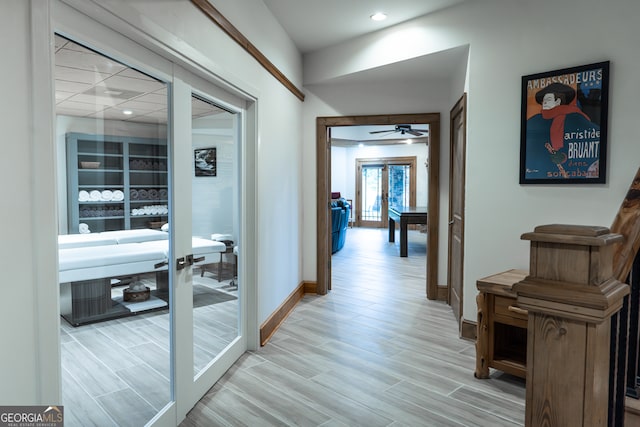 corridor with light hardwood / wood-style flooring and french doors