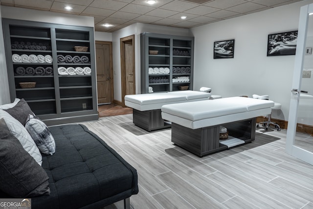 game room featuring hardwood / wood-style floors and a drop ceiling