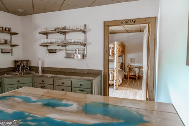 kitchen featuring wood-type flooring, a paneled ceiling, and sink