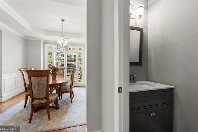 5 Arabian Ave, Alpharetta, GA 30004 - dining area featuring a wainscoted wall, crown molding, light wood-style flooring, a tray ceiling, and a notable chandelier