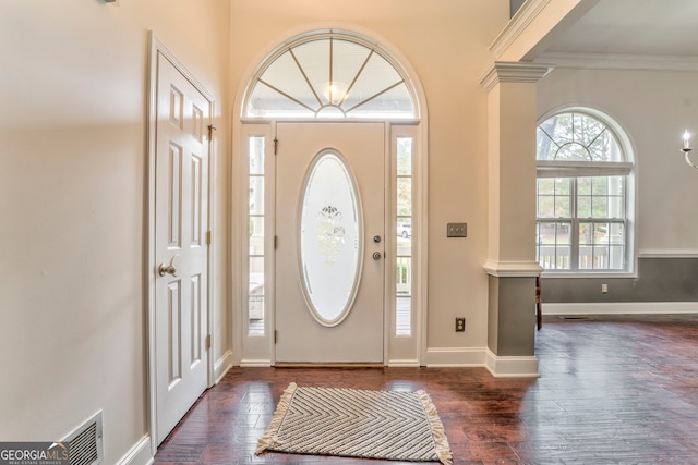 entrance foyer featuring dark hardwood / wood-style flooring, ornamental molding, and ornate columns