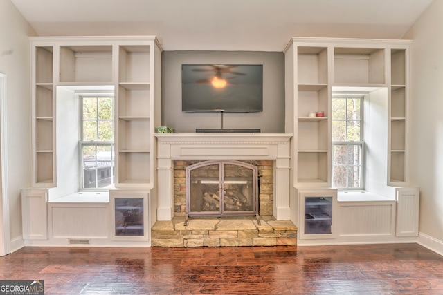 unfurnished living room featuring dark wood-type flooring, a fireplace, and a healthy amount of sunlight