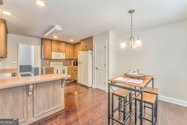 kitchen with a chandelier, decorative light fixtures, dark hardwood / wood-style flooring, a breakfast bar, and white appliances