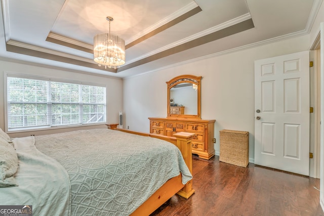 bedroom with dark wood-type flooring, ornamental molding, an inviting chandelier, and a tray ceiling