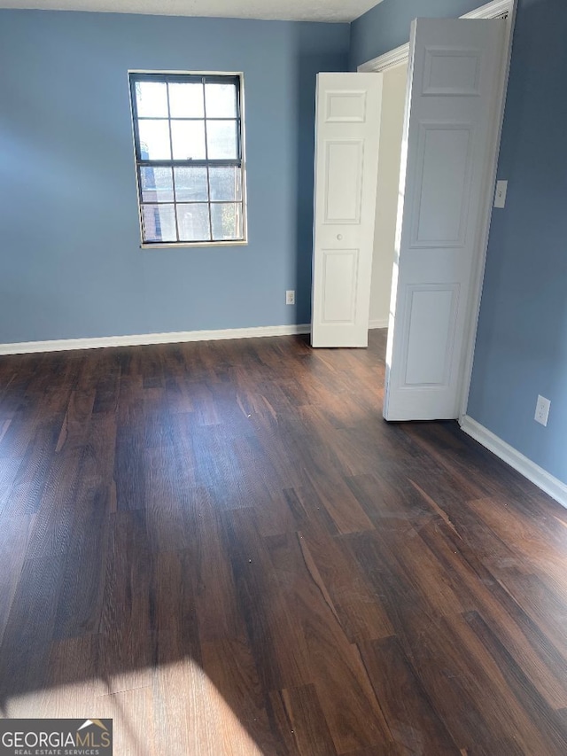 unfurnished room with dark hardwood / wood-style flooring