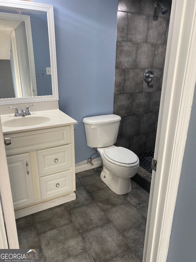 bathroom featuring toilet, vanity, and a tile shower