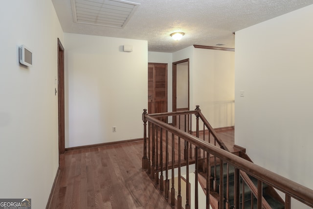 corridor with a textured ceiling and dark hardwood / wood-style floors