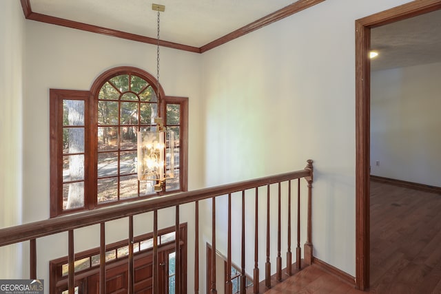 corridor featuring wood-type flooring, a textured ceiling, ornamental molding, and a notable chandelier