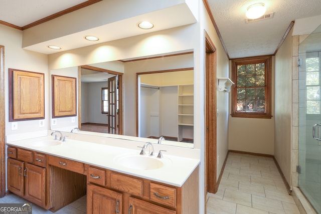 bathroom featuring vanity, crown molding, a shower with shower door, and a textured ceiling