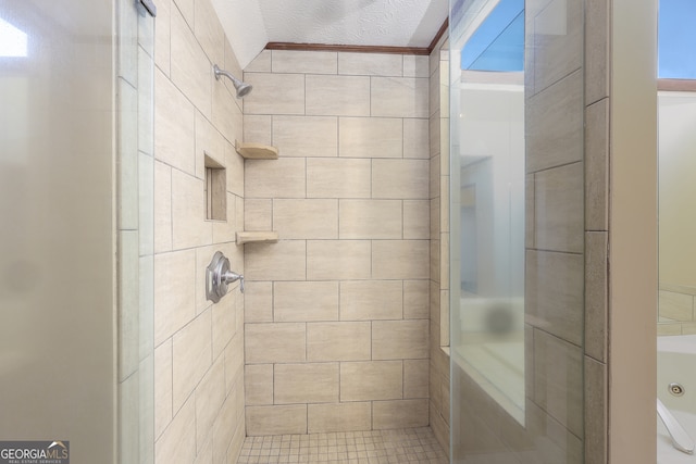 bathroom featuring a tile shower and a textured ceiling