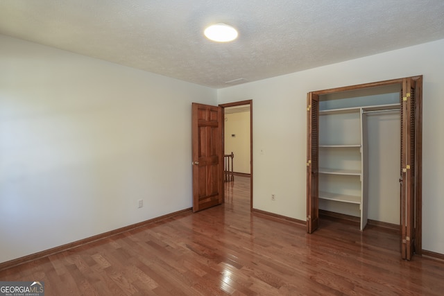 unfurnished bedroom with hardwood / wood-style floors, a textured ceiling, and a closet