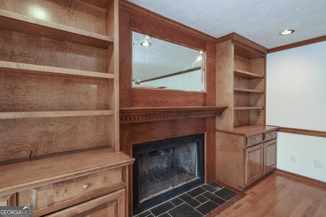 unfurnished living room with hardwood / wood-style floors, a textured ceiling, and ornamental molding