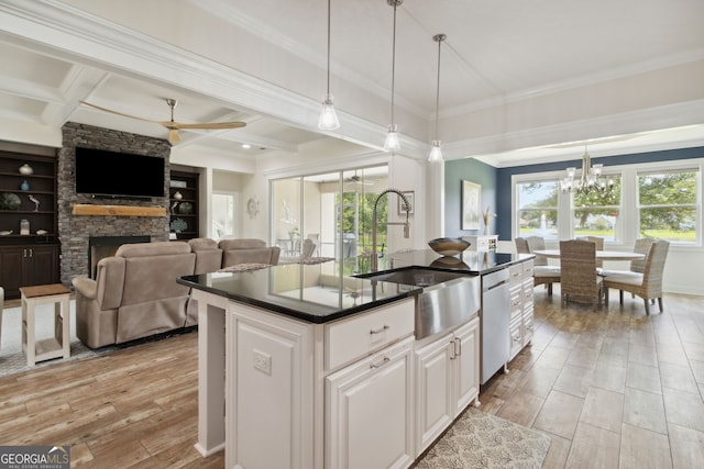 kitchen with light hardwood / wood-style floors, a fireplace, an island with sink, coffered ceiling, and white cabinets