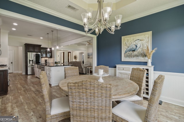 dining space featuring ceiling fan with notable chandelier, light hardwood / wood-style floors, and crown molding