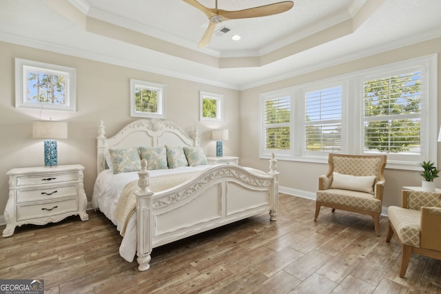 bedroom featuring ceiling fan, a tray ceiling, hardwood / wood-style flooring, and ornamental molding