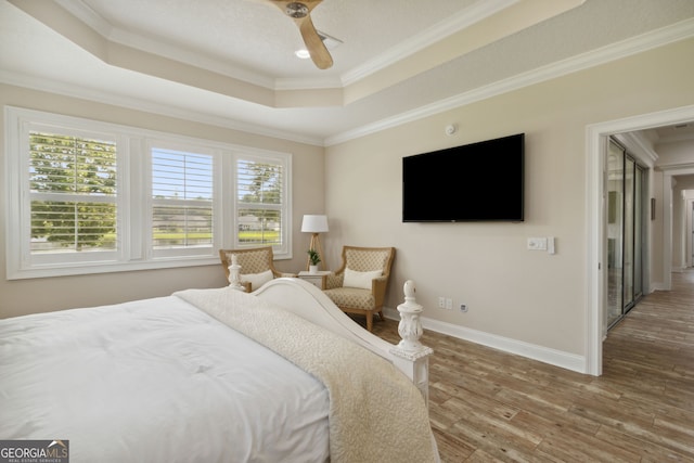 bedroom with ornamental molding, multiple windows, hardwood / wood-style flooring, and ceiling fan